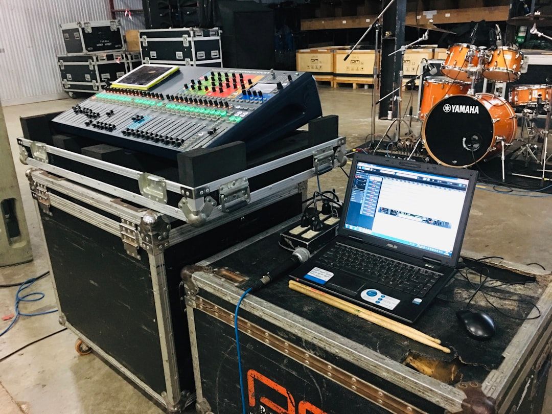 Console de mixage numérique, ordinateur portable et batterie prêts pour un concert.